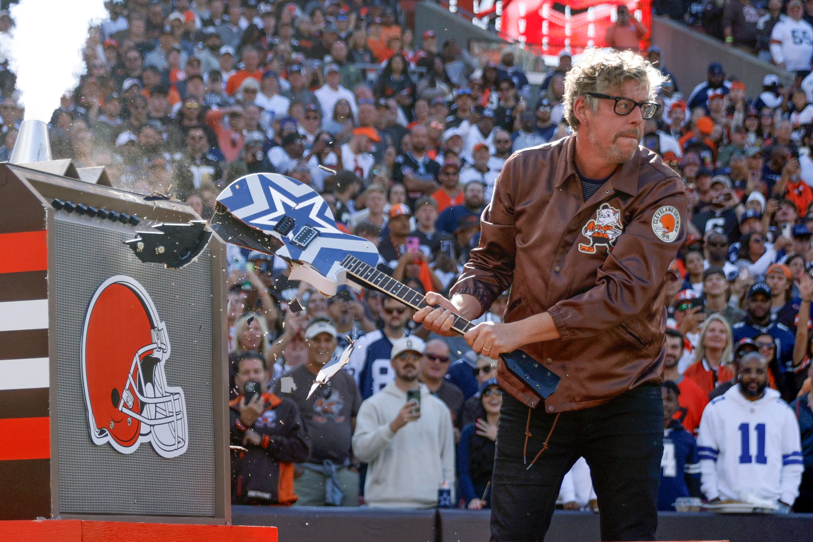 Patrick Carney of The Black Keys smashes a Dallas Cowboys themed guitar before a game...