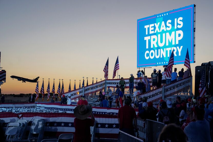 Supporters of former President Donald Trump watch his plane takeoff after a campaign rally...