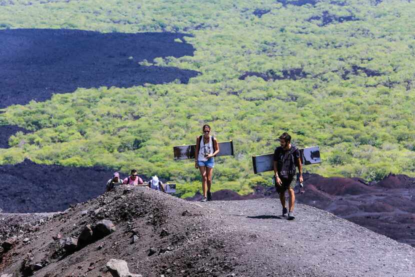 Tourists climb the Cerro Negro volcano with their boards. The hike up to the peak is steep...