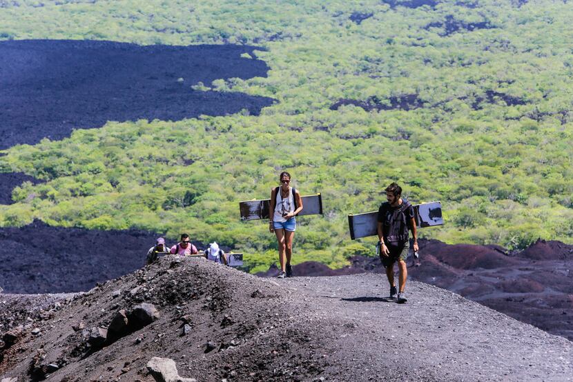 Tourists climb the Cerro Negro volcano with their boards. The hike up to the peak is steep...