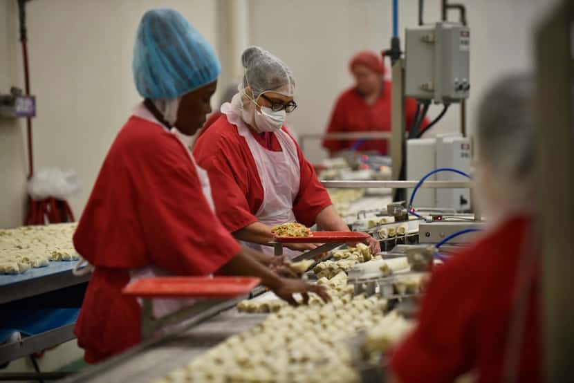 Employees inspect egg rolls as they move on conveyor belts for frying at the Van's Kitchen...
