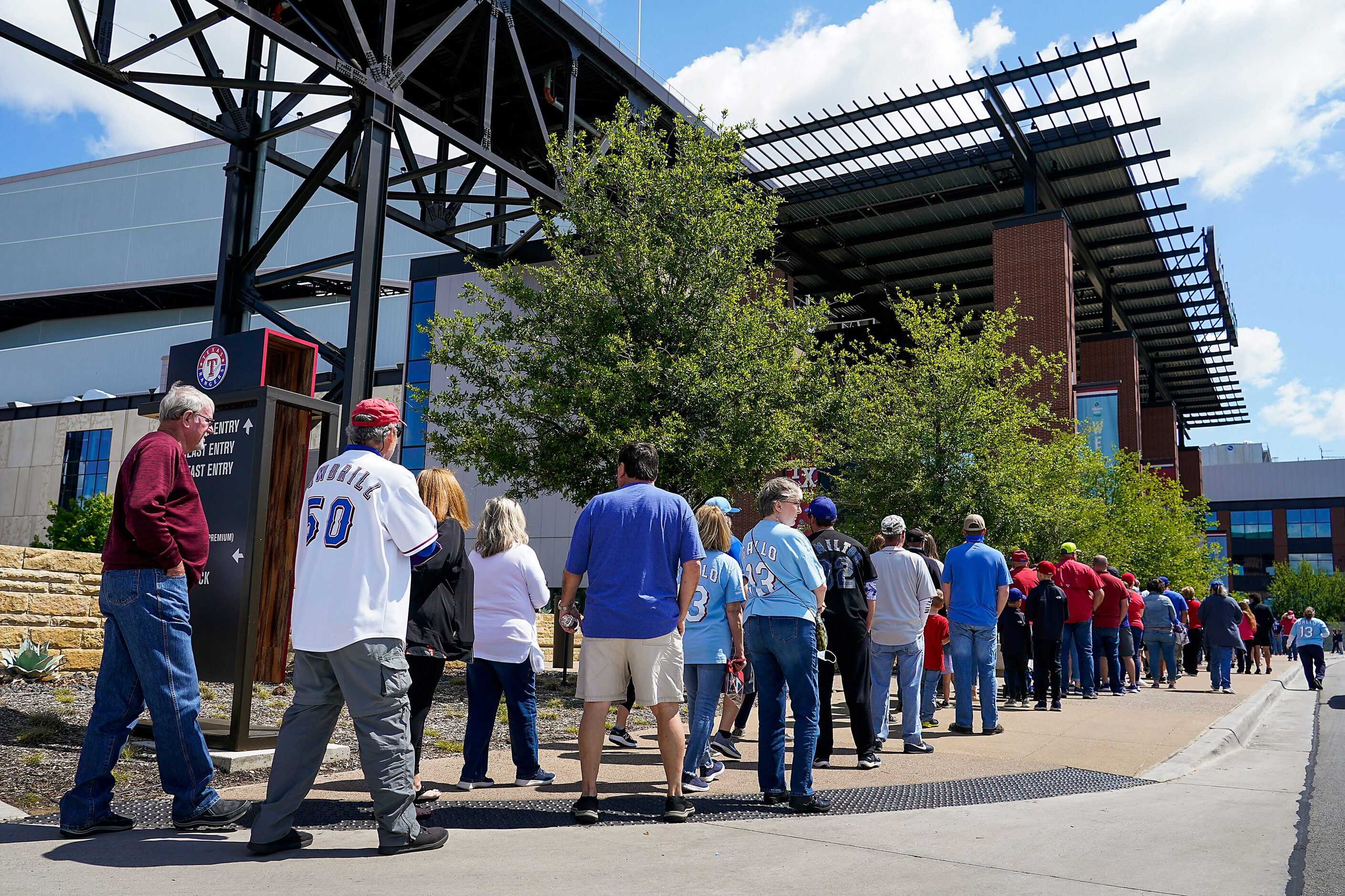 Fans wait in line to go enter the stadium before a game between the Texas Rangers and the...