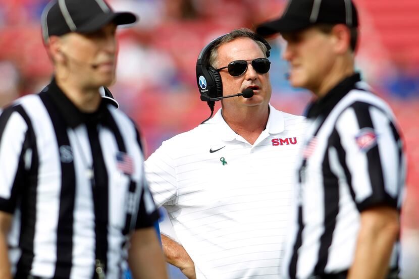 SMU head coach Sonny Dykes watches a replay on the scoreboard screen as game officials call...