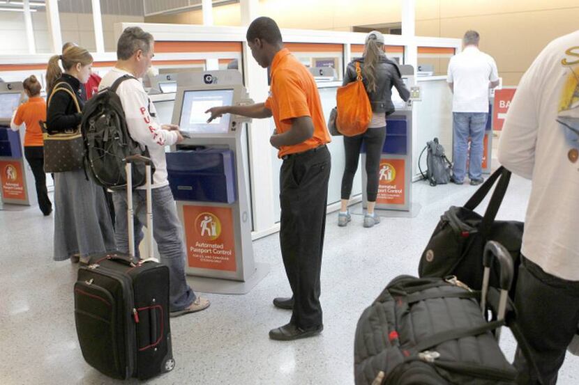  Benjamin Thompson (center) helps passengers use the Automated Passport Control system. The...