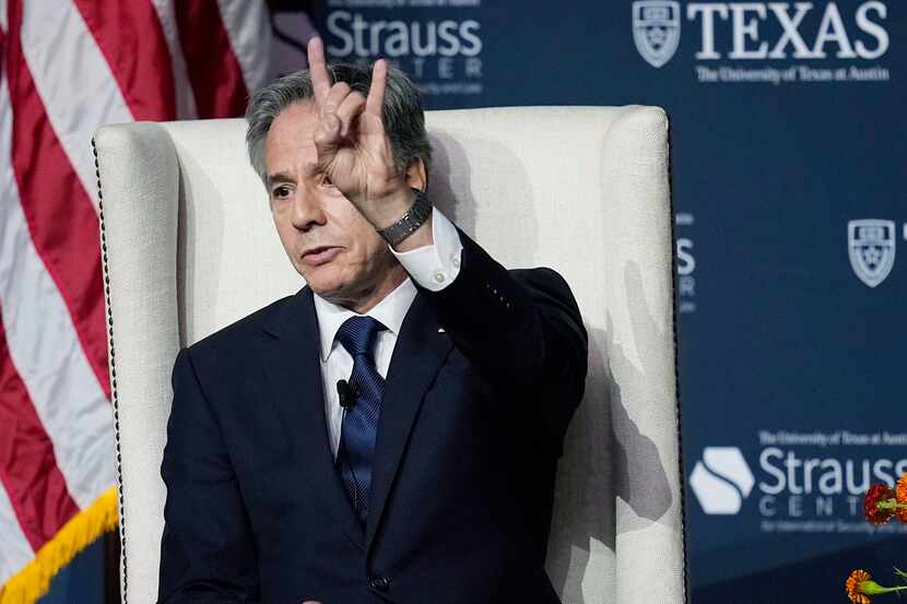 Secretary of State Antony Blinken flashes a 'Hook'em Horns' during a visit to the University...