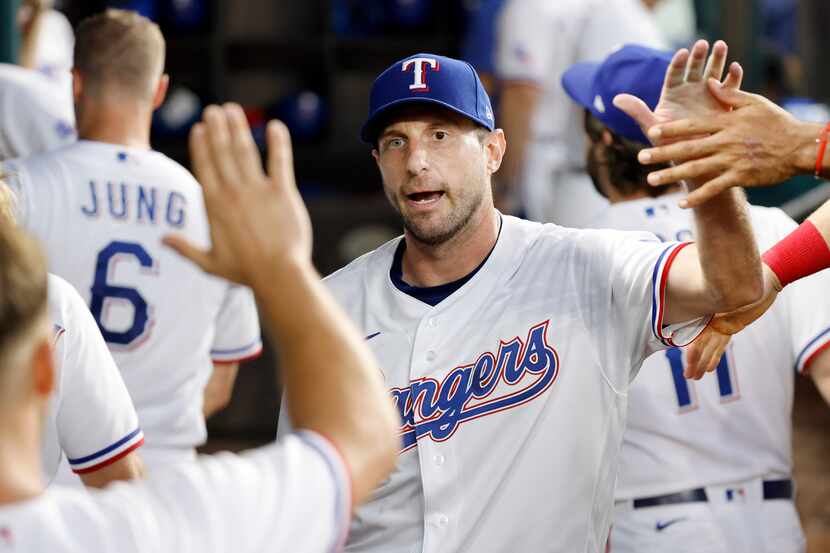 Texas Rangers starting pitcher Max Scherzer (31) delivers and receives fist bumps and...