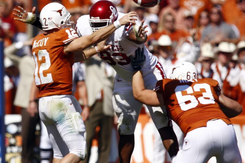 Texas quarterback Colt McCoy (12 - left) gets a pass away despite onrushing Oklahoma...