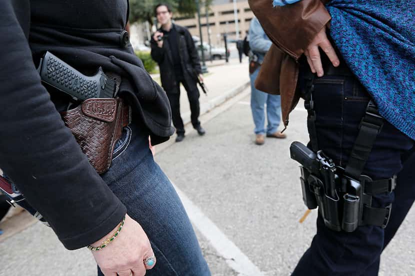 Dos personas muestran las pistolas que portan en fundas, durante una demostración frente al...