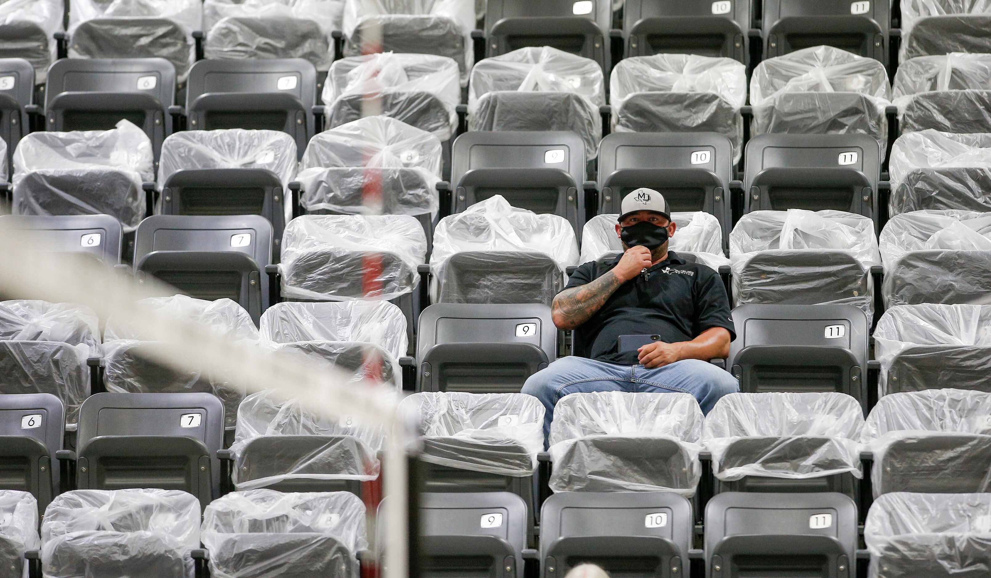 A spectator adjusts his masks with groups of seats with plastic bags cordon off to promote...