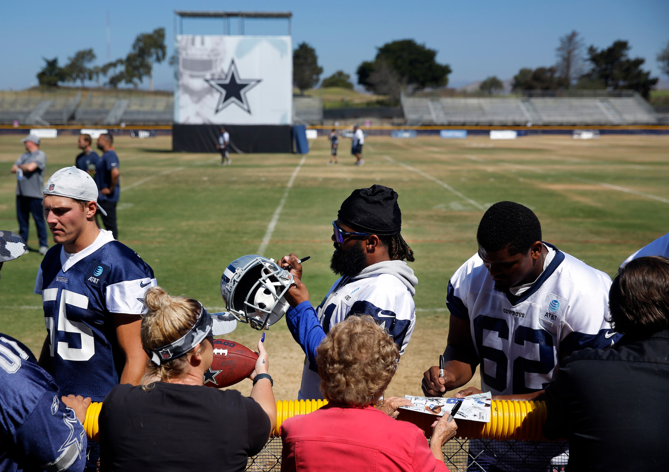 Dallas Cowboys running back Ezekiel Elliott (center) signs autographs for volunteers...