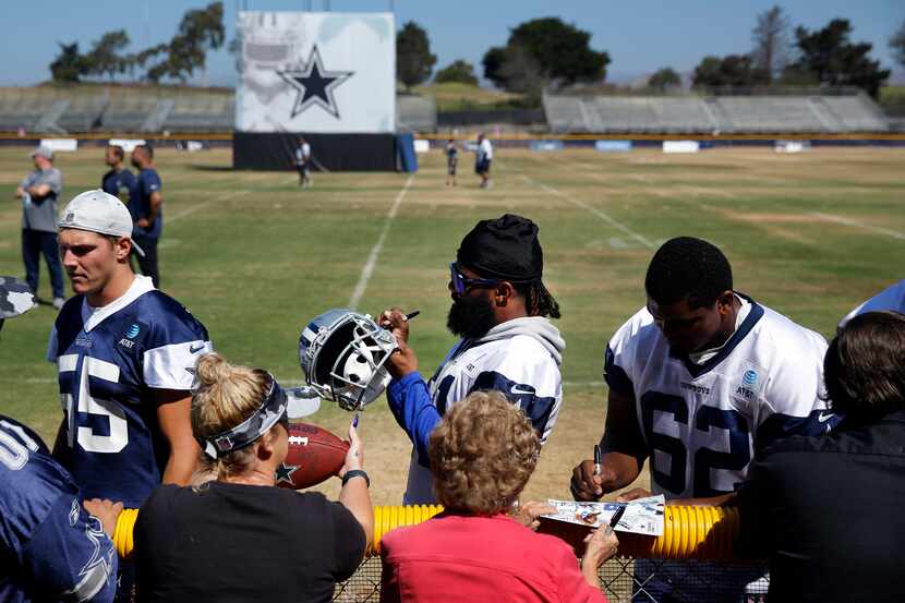 Dallas Cowboys running back Ezekiel Elliott (center) signs autographs for volunteers...