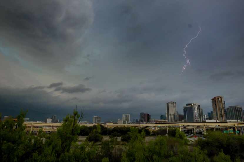 A file photo shows lighting lighting up the sky as storm clouds gathered over downtown...