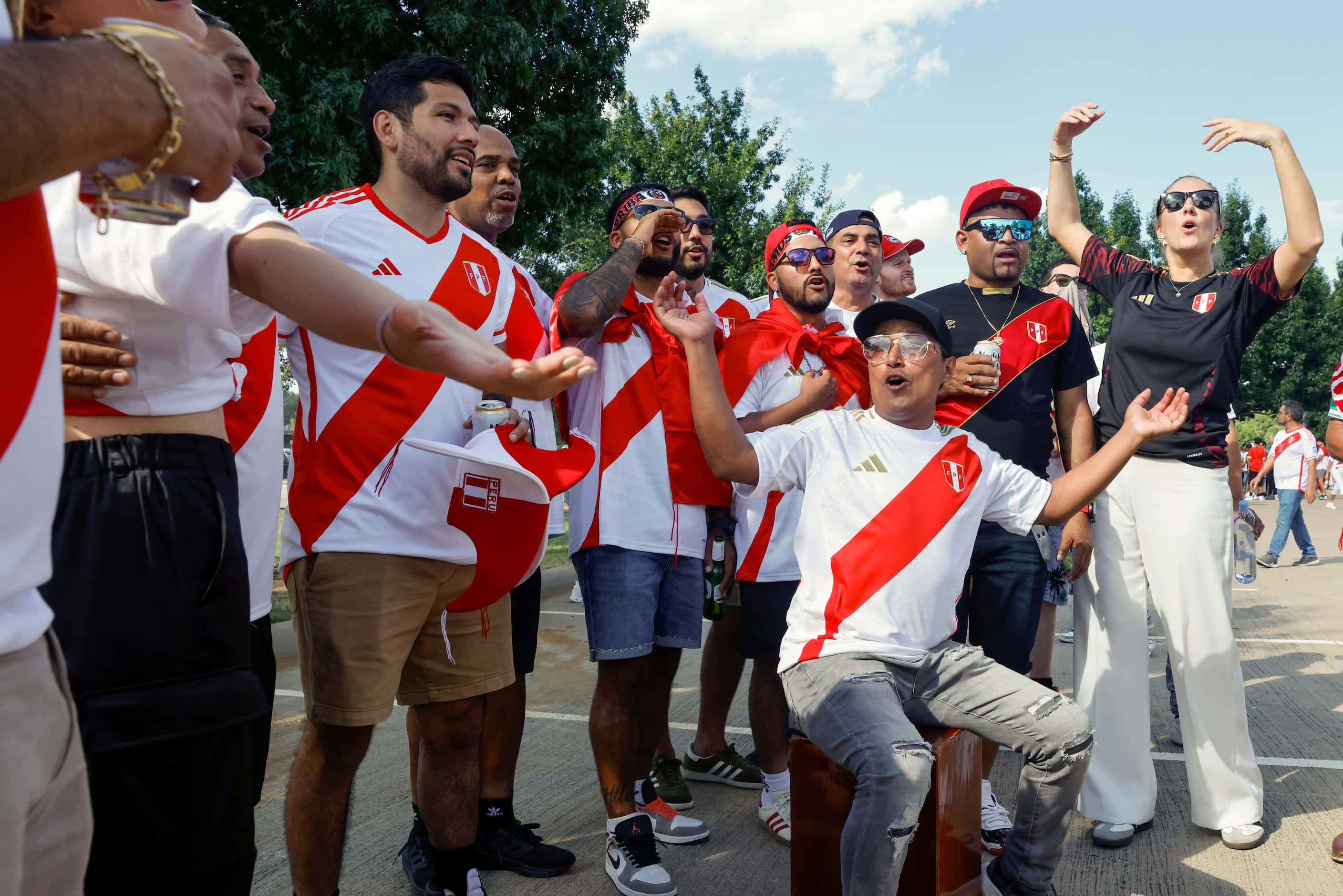 Peru fans cheer and dance as Sergio Herrera (seated) of Dallas plays a Peruvian box drum...