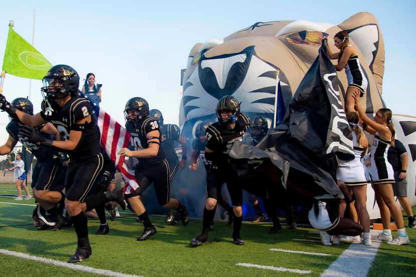 The Mansfield Tigers take the field prior to the start of a District 11-6A high school...