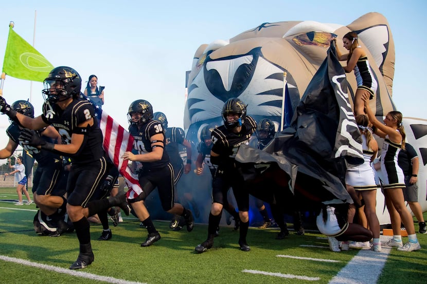 The Mansfield Tigers take the field prior to the start of a District 11-6A high school...