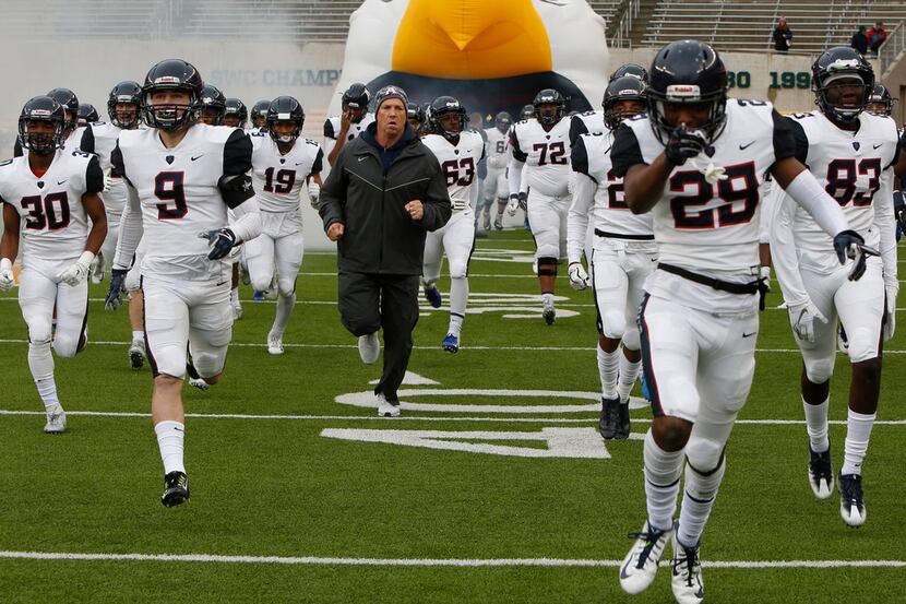 Allen head coach Terry Gambill leads his Eagles players from the team inflatable just prior...