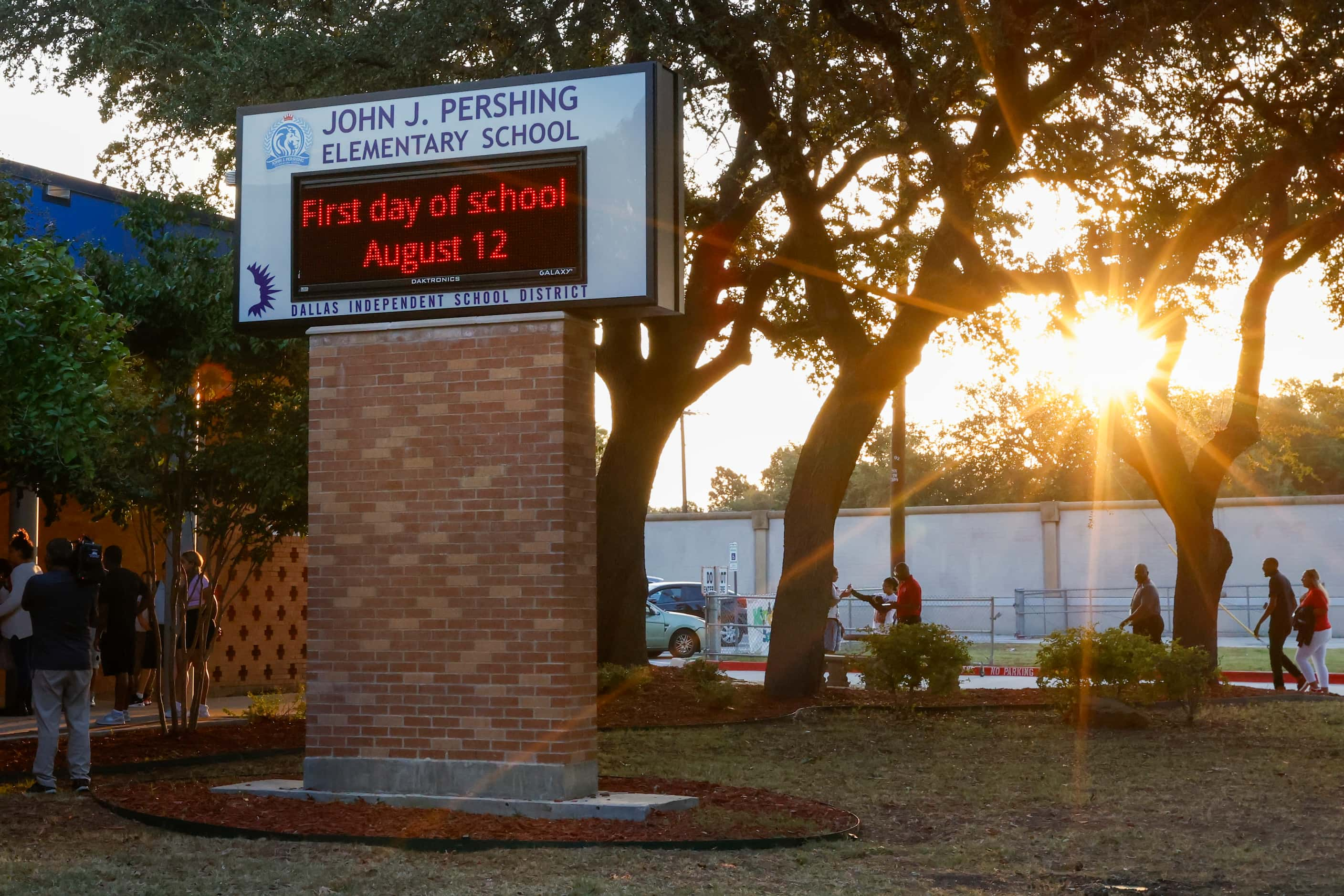 The sun rises over students and their families as they arrive for the first day of class at...