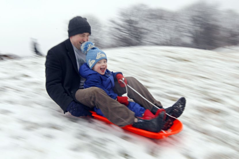 Matt Redmond, 3, and his father, Mike, sled down a hill after an overnight snowfall in...
