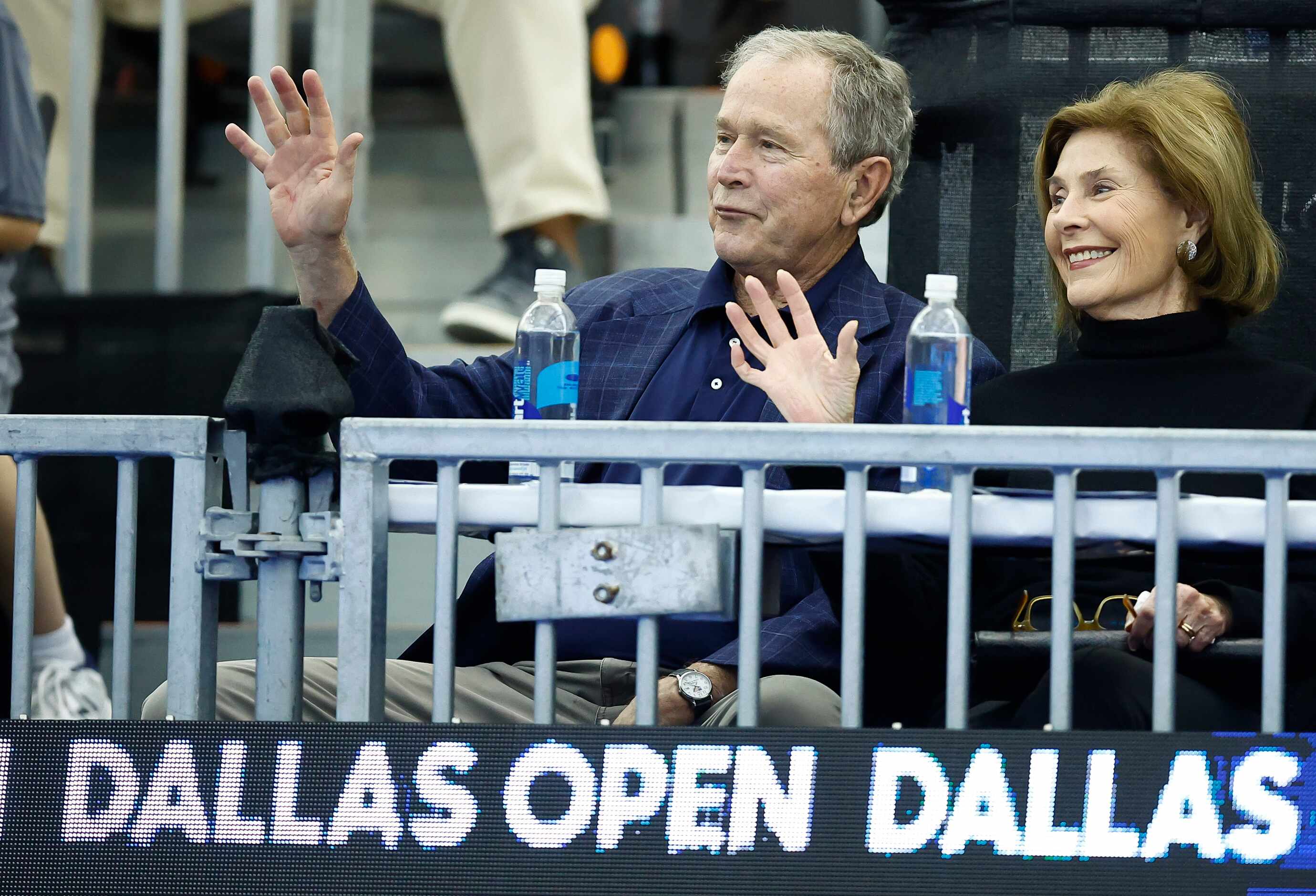 Former President George W. Bush and First Lady Laura Bush wave to fans before the start of...