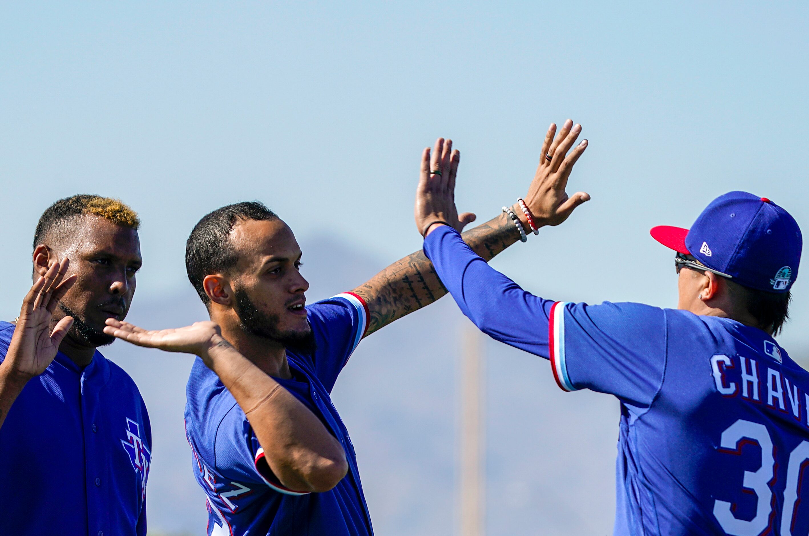 Texas Rangers pitcher Jonathan Hernandez (center) high fives pitcher Jesse Chavez during a...