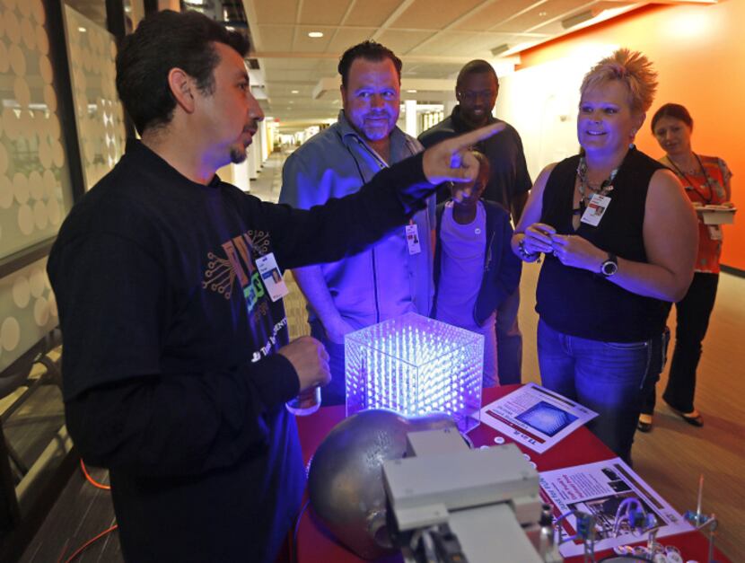 Luis Flores explains items he designed or built with TI equipment to Eddie Accomando of...