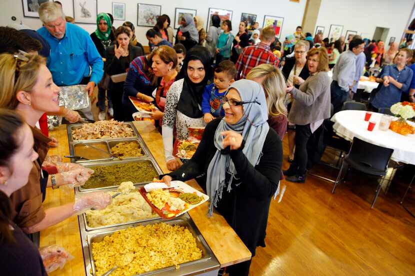 Iraqi refugee Shukriyah Merza (right) thanks volunteers for her meal during the 6th annual...