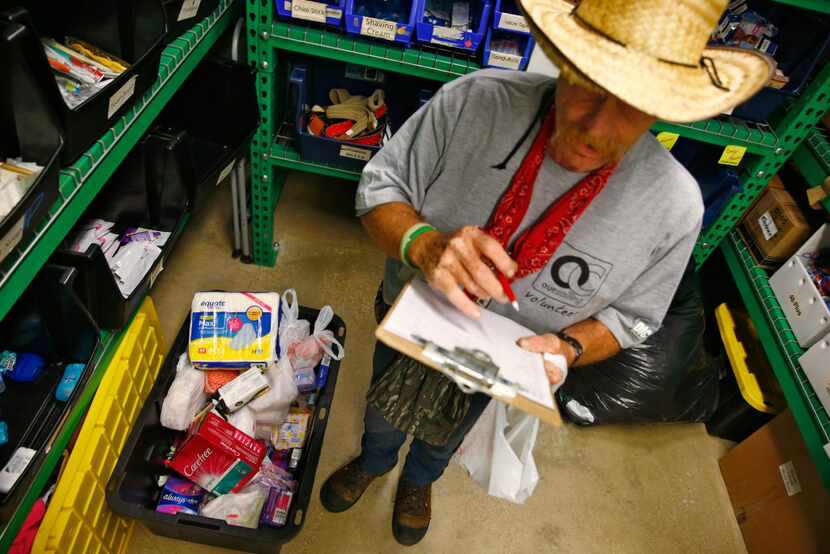 Volunteer James LaBonte picks out items for the homeless next to a box of feminine hygiene...
