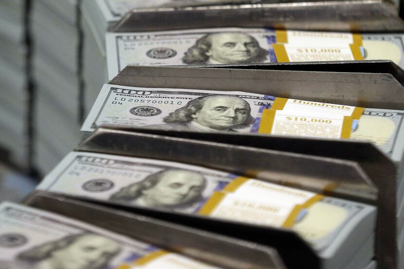 In this Sept. 24, 2013 photo, freshly-cut stacks of $100 bills make their way down the line...