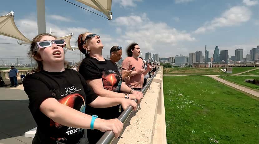 Visitors to Dallas use solar glasses to watch as the moon transits the sun on during a total...