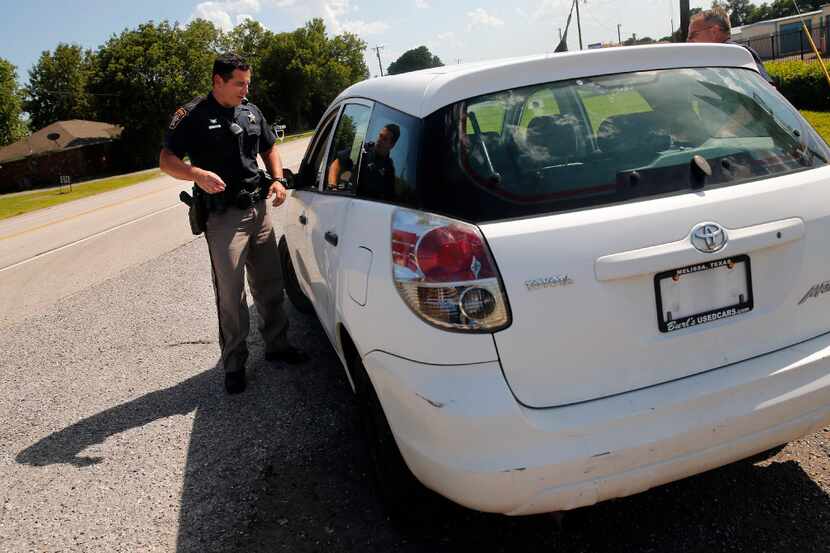 Collin County Sheriff's Dept. deputy Rodney Tackett visits with a driver whose car was...