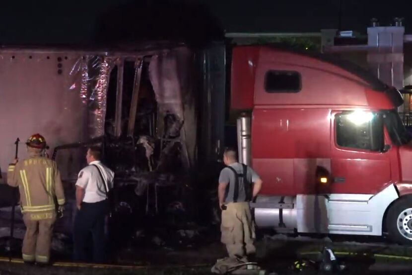 Fire crews survey a damaged section of an 18-wheeler that caught fire Wednesday morning in...