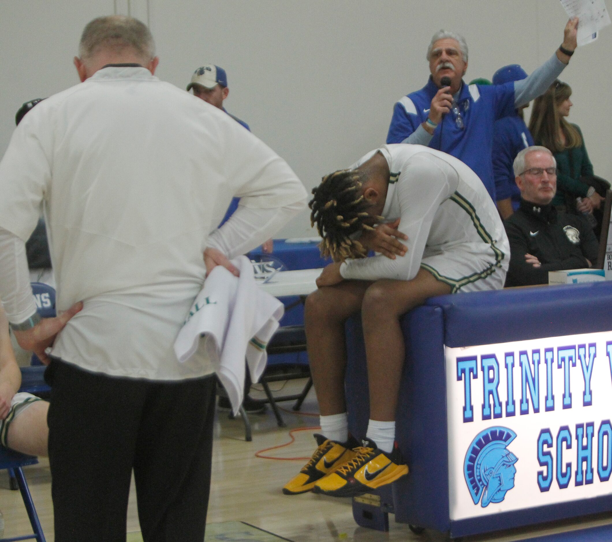 Greenhill's Micah Robinson (5), center, sits in shock as head coach Joey Sims, left, lowers...