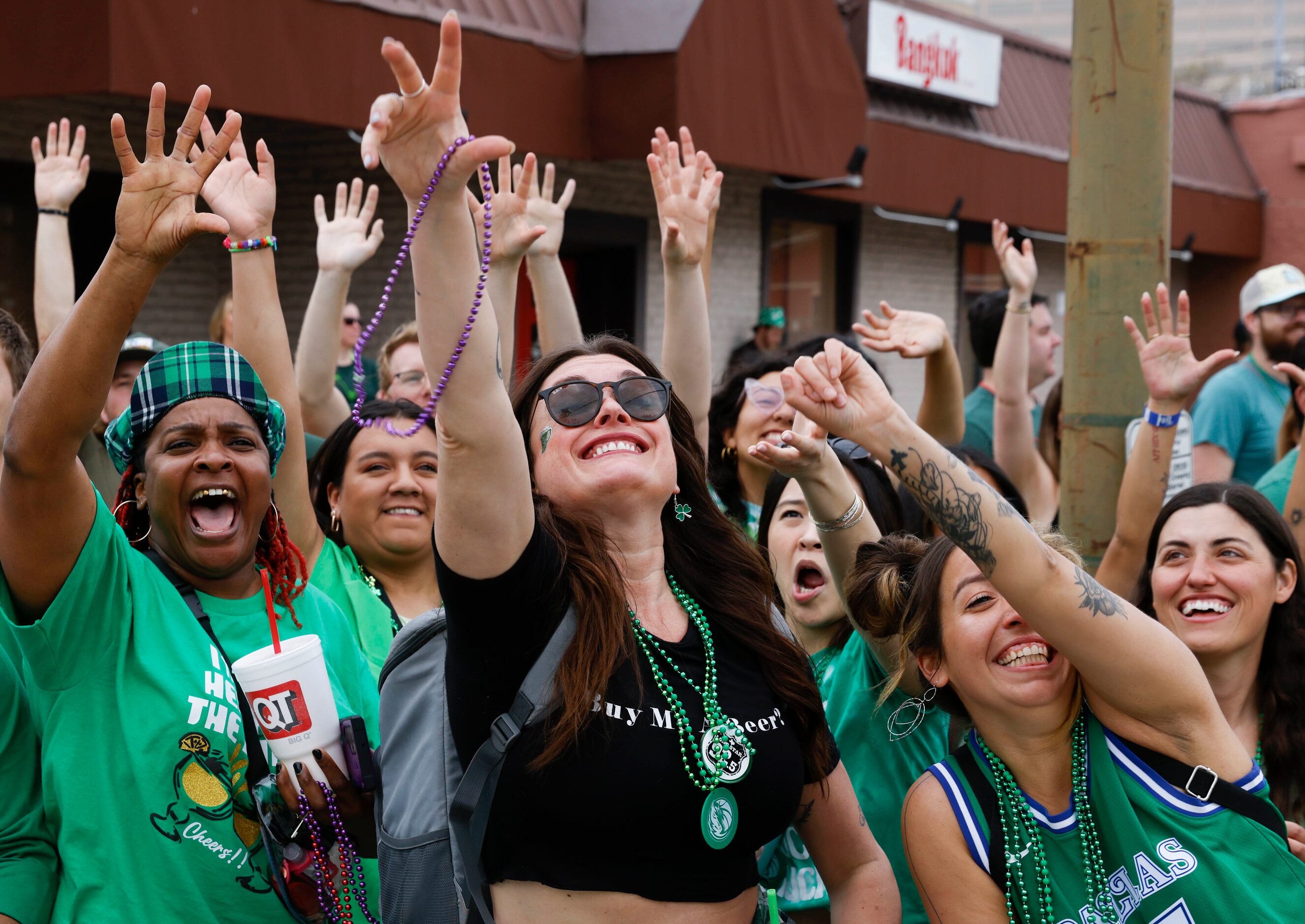 Attending crowd tries to catch green bead necklaces tossed by marchers during a Saint...