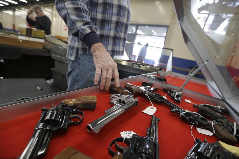  In this Friday, Feb. 6, 2015 photo, a dealer arranges handguns in a display case in advance...