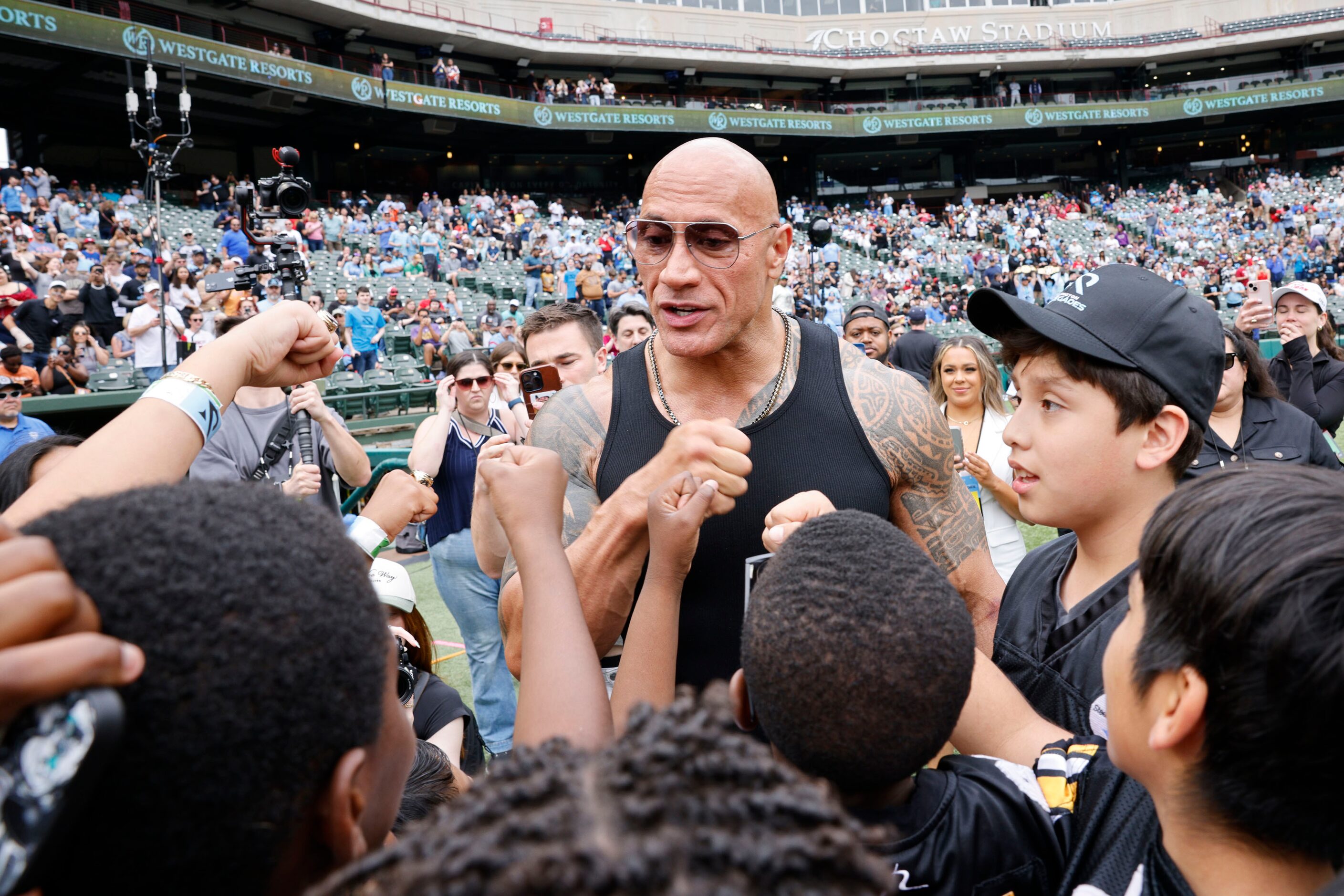 Dwayne "The Rock" Johnson speaks to children before a football game between the Arlington...