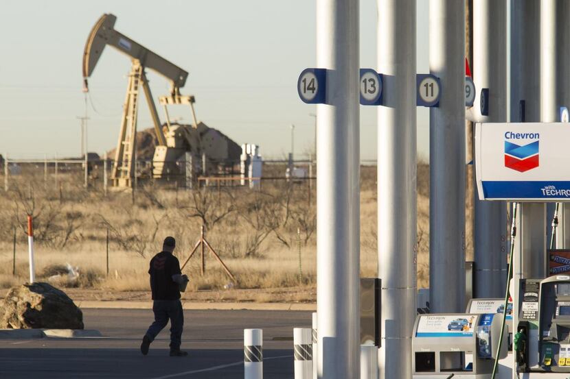 As drivers pay less  at the pump at a Chevron station in Midland, a pump jack in the...