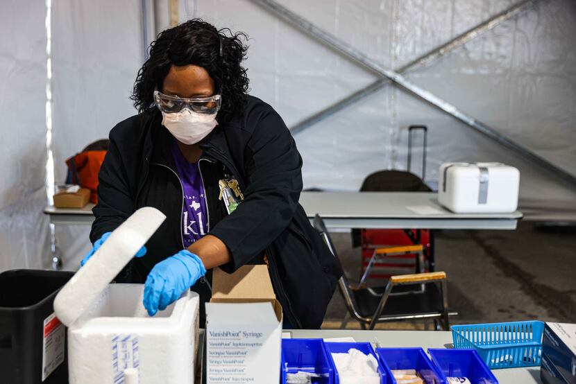 Nurse Lisa Taylor grabs a Pfizer-BioNTech vaccine vial from its container at Ellis Davis...