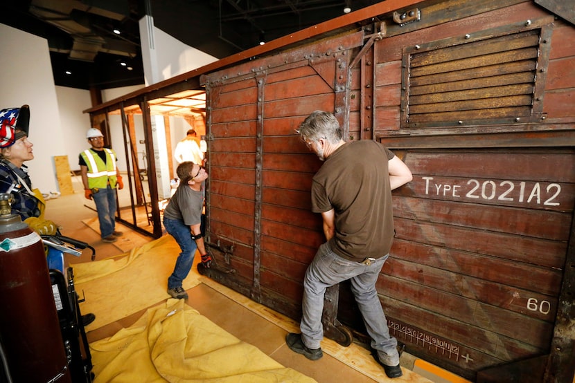 Carpenter Jeff Green (right) and lead carpenter Dennis Manske erect a door on the rail car...