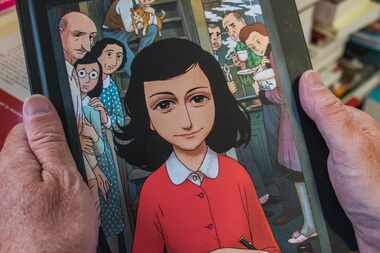 A man holds a copy of the graphic novel version of "The Diary of Anne Frank," by Israeli...