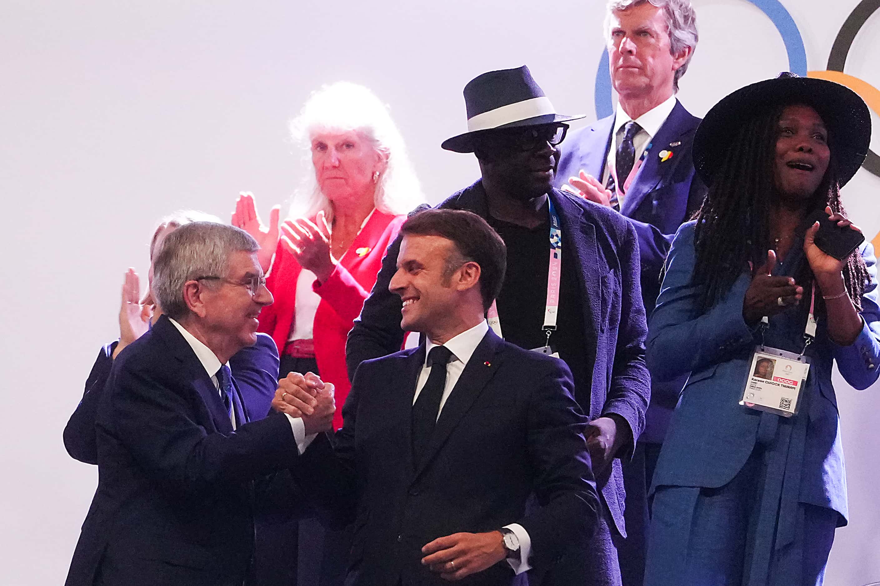 French President Emmanuel Macron (center) shakes hands with Thomas Bach, President of the...
