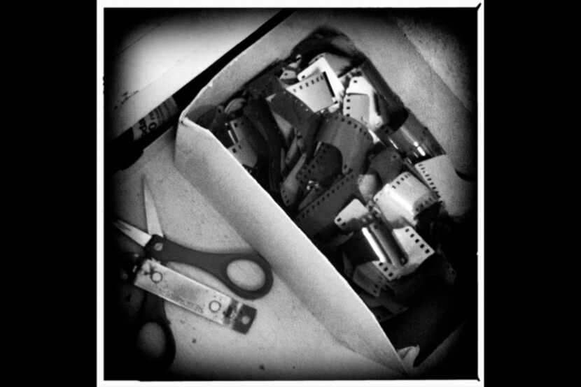 A can opener used for opening film canisters, scissors and a box of film snips sits in the...