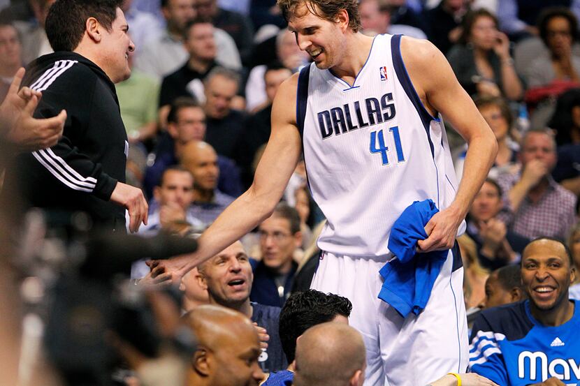 Mavericks power forward Dirk Nowitzki receives a round of applause and a hand slap from...