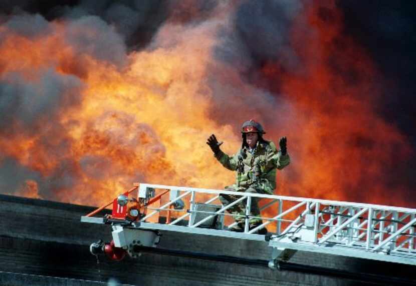 A Dallas firefighter gestures when the water pressure dropped suddenly while battling a...