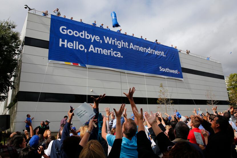 Southwest Airlines employees wave their hands as other employees throw t-shirts off the roof...