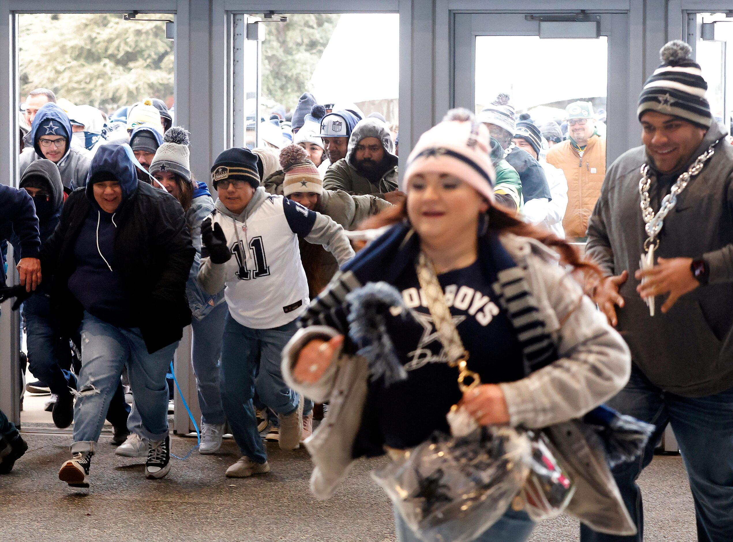 Dallas Cowboys and Green Bay Packers fans race through the west plaza doors in hope of...