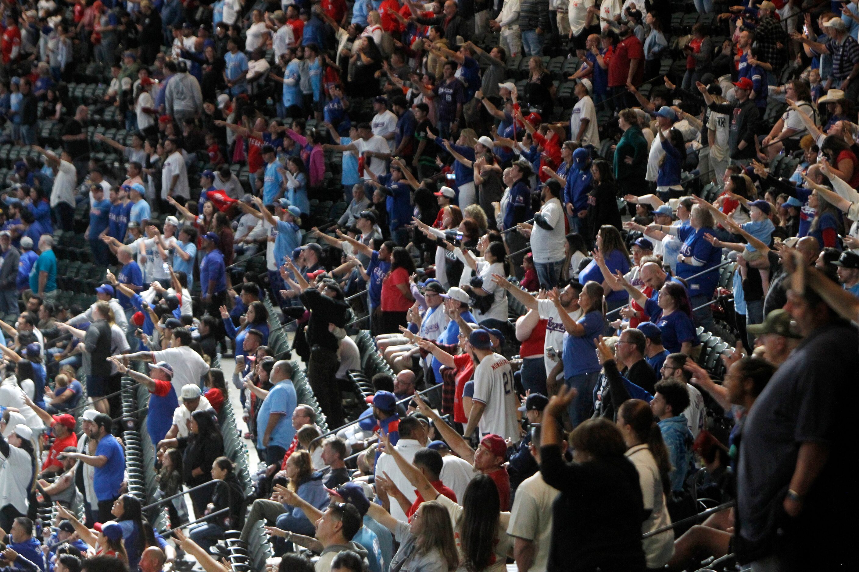 Texas Rangers fans stand at the prompting of Rangers public address announcer Chuck Morgan...