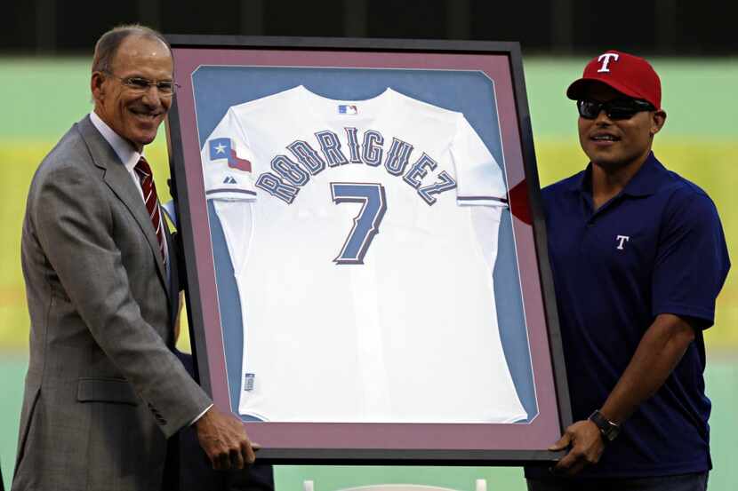 Tom Grieve (left) and Ivan Rodriguez hold up Rodriguez's framed jersey during his retirement...
