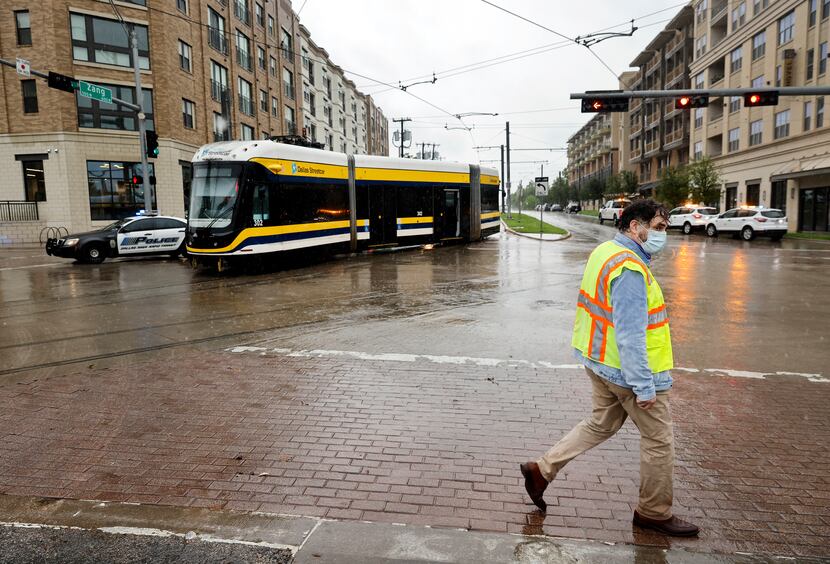 A man passes by the DART Dallas Streetcar which derailed at Zang Blvd. and Davis Street in...