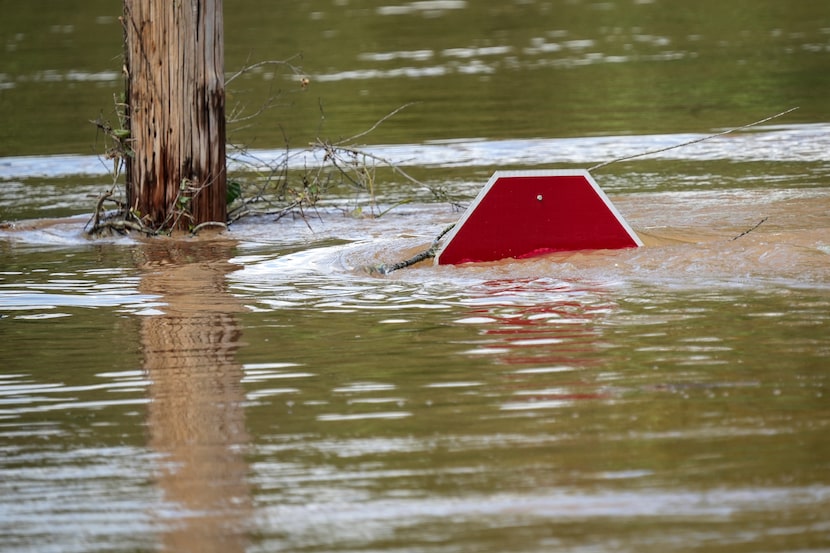 A stop sign can be barely seen above a flooded parking lot after torrential rain from...