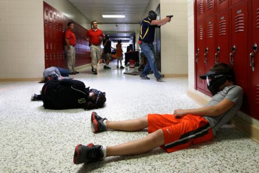 A Clarksville schools faculty member (top right) carries an air-powered practice handgun to...